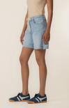 Person wearing light blue denim shorts on a beige background
