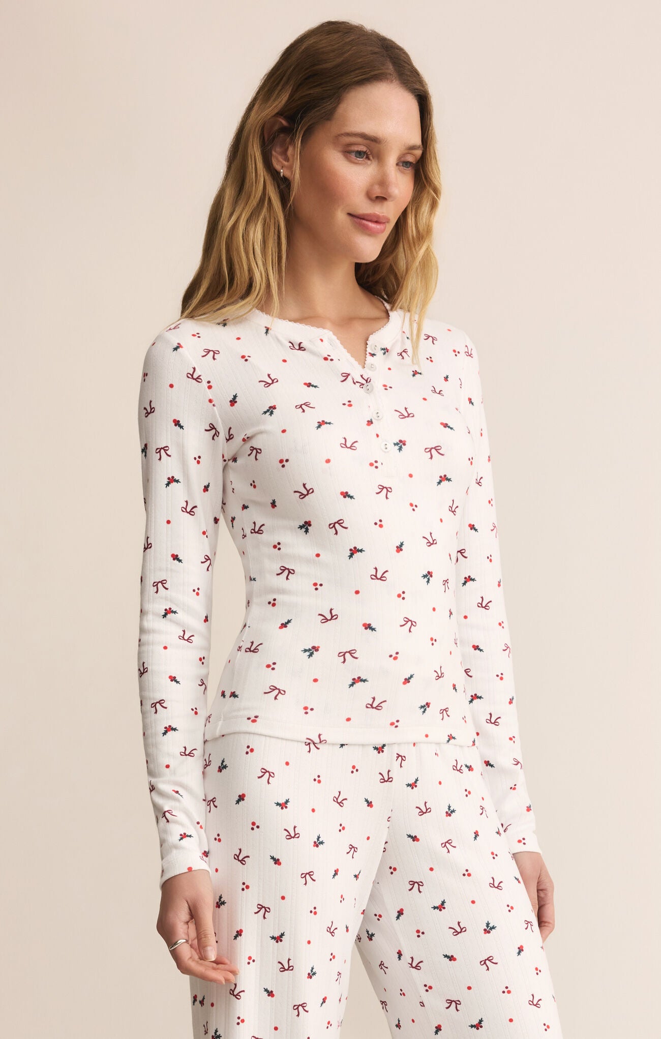 Woman wearing a white long-sleeve top with red floral pattern on a beige background