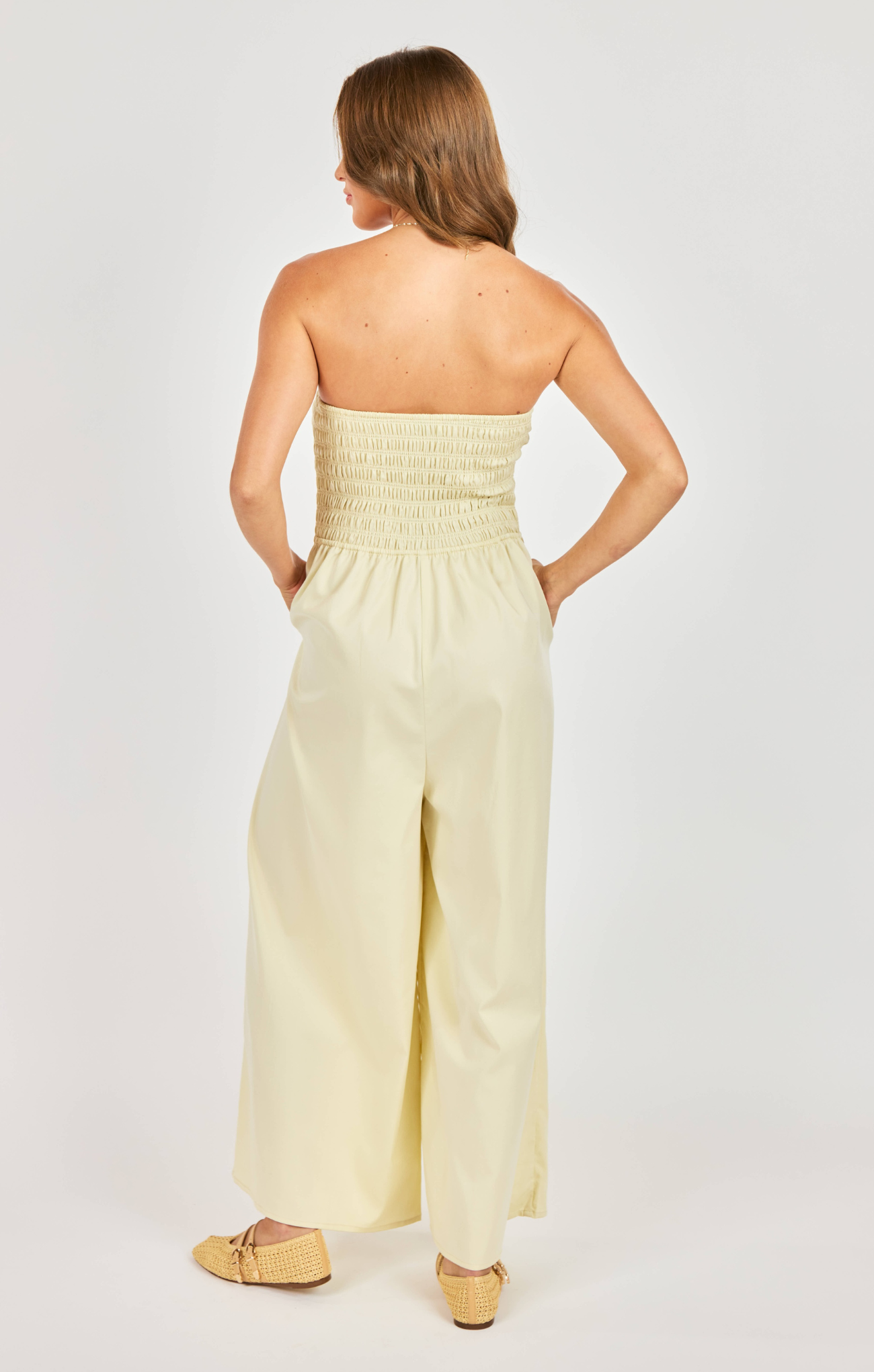 Woman wearing a strapless yellow jumpsuit on a white background