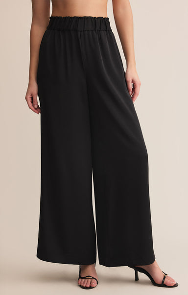 Black wide-leg pants worn by a person on a beige background