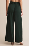 Dark green wide-leg pants worn by a person on a beige background