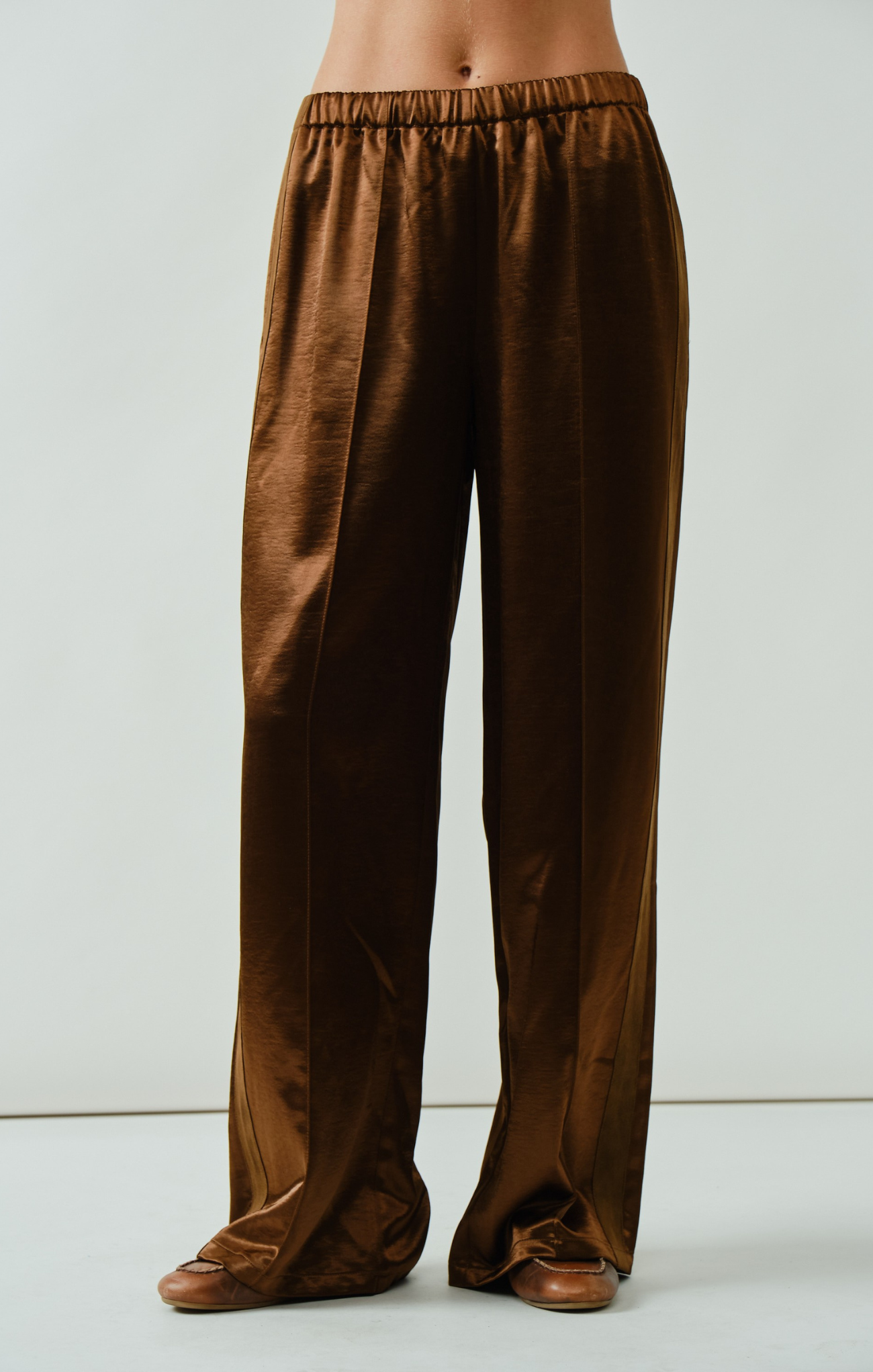 Brown satin pants on a plain background