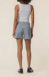Person wearing a light blue tank top and checkered shorts on a beige background