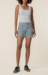 Woman wearing a white tank top and blue checkered shorts on a beige background