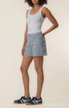 Woman wearing a light blue tank top and striped shorts on a beige background