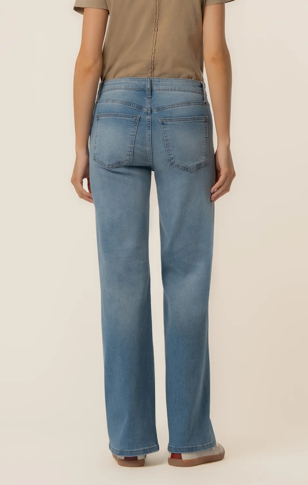 Person wearing blue jeans on a beige background