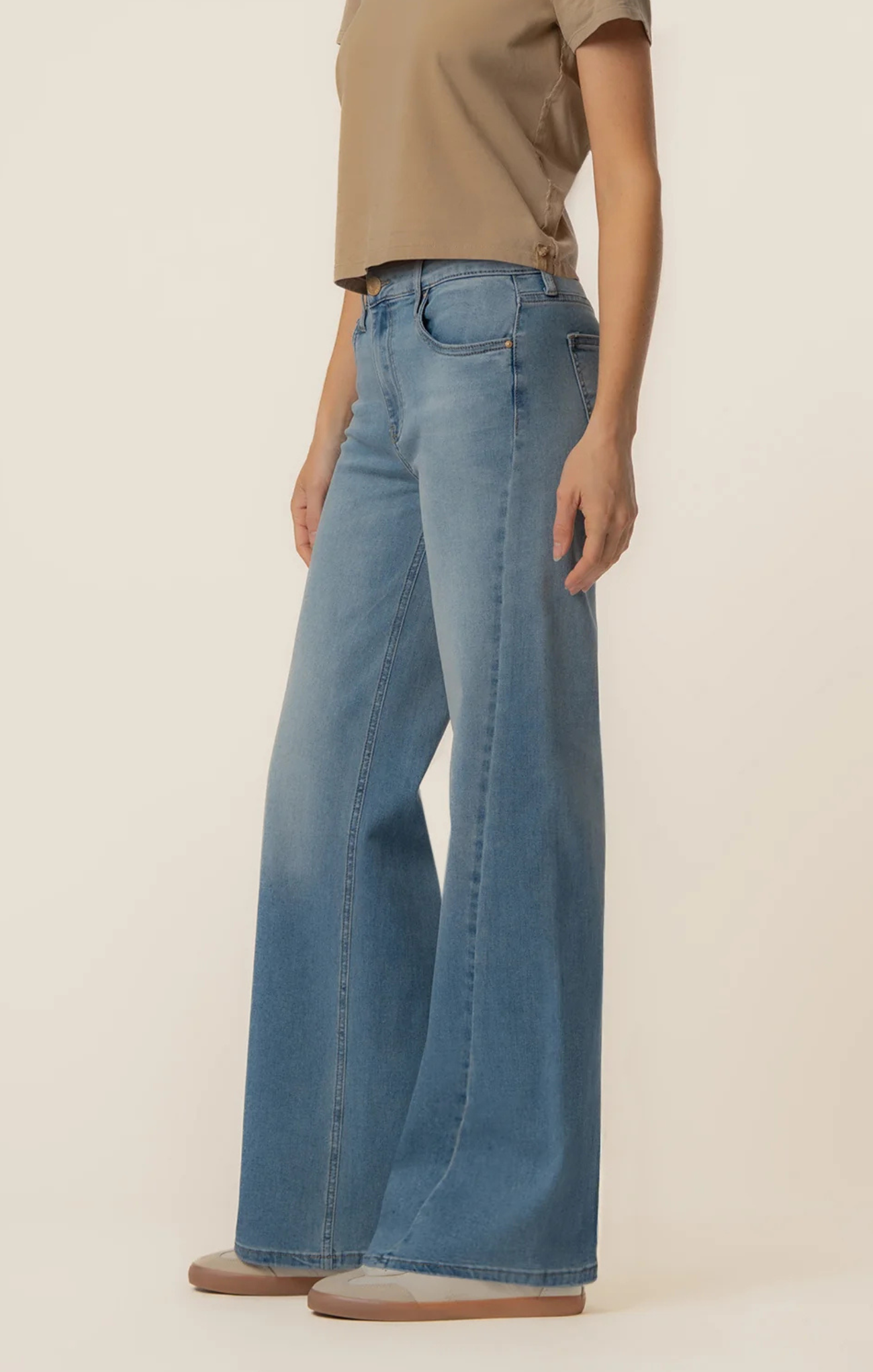 Person wearing light blue jeans and a beige shirt on a plain background