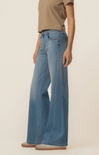 Person wearing light blue jeans and a beige shirt on a plain background
