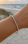 Silver beaded bracelet on a wrist with a beach background