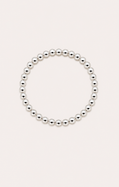 Silver beaded bracelet on a wrist with a beach background