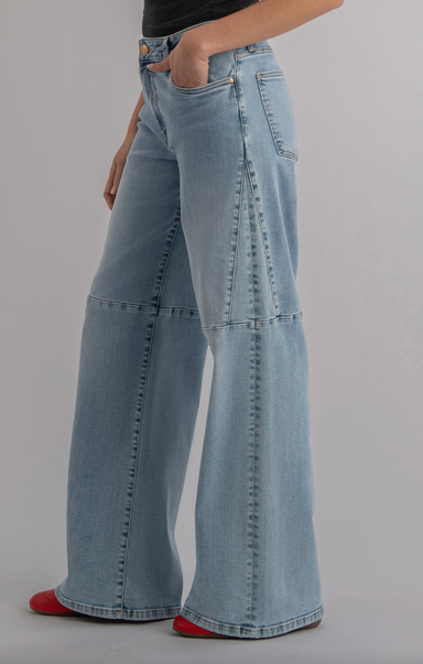 Light blue wide-leg jeans worn by a person on a gray background
