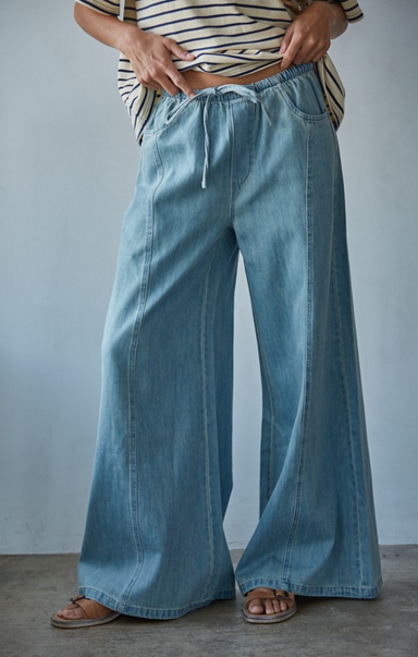 Person wearing wide-leg blue jeans against a plain background
