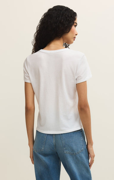 Woman wearing a white t-shirt and blue jeans against a plain background