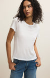 Woman wearing a white t-shirt and blue jeans against a plain background