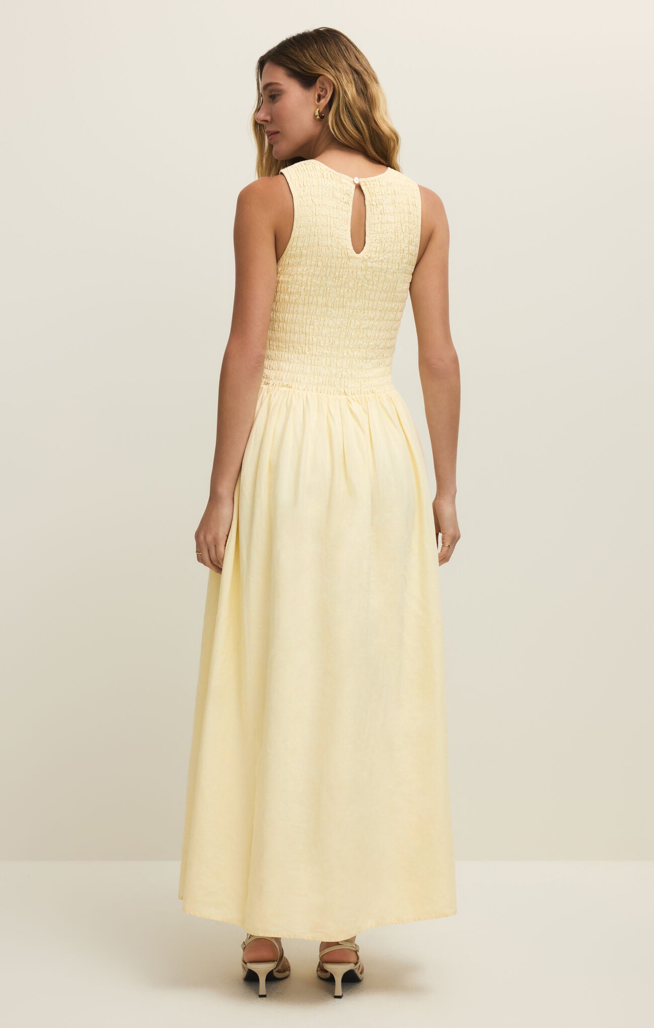 Woman wearing a light yellow dress against a white background
