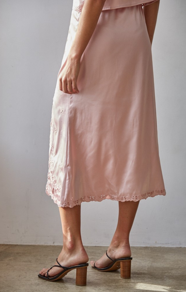 Person wearing a pink satin slip dress with lace trim against a plain background