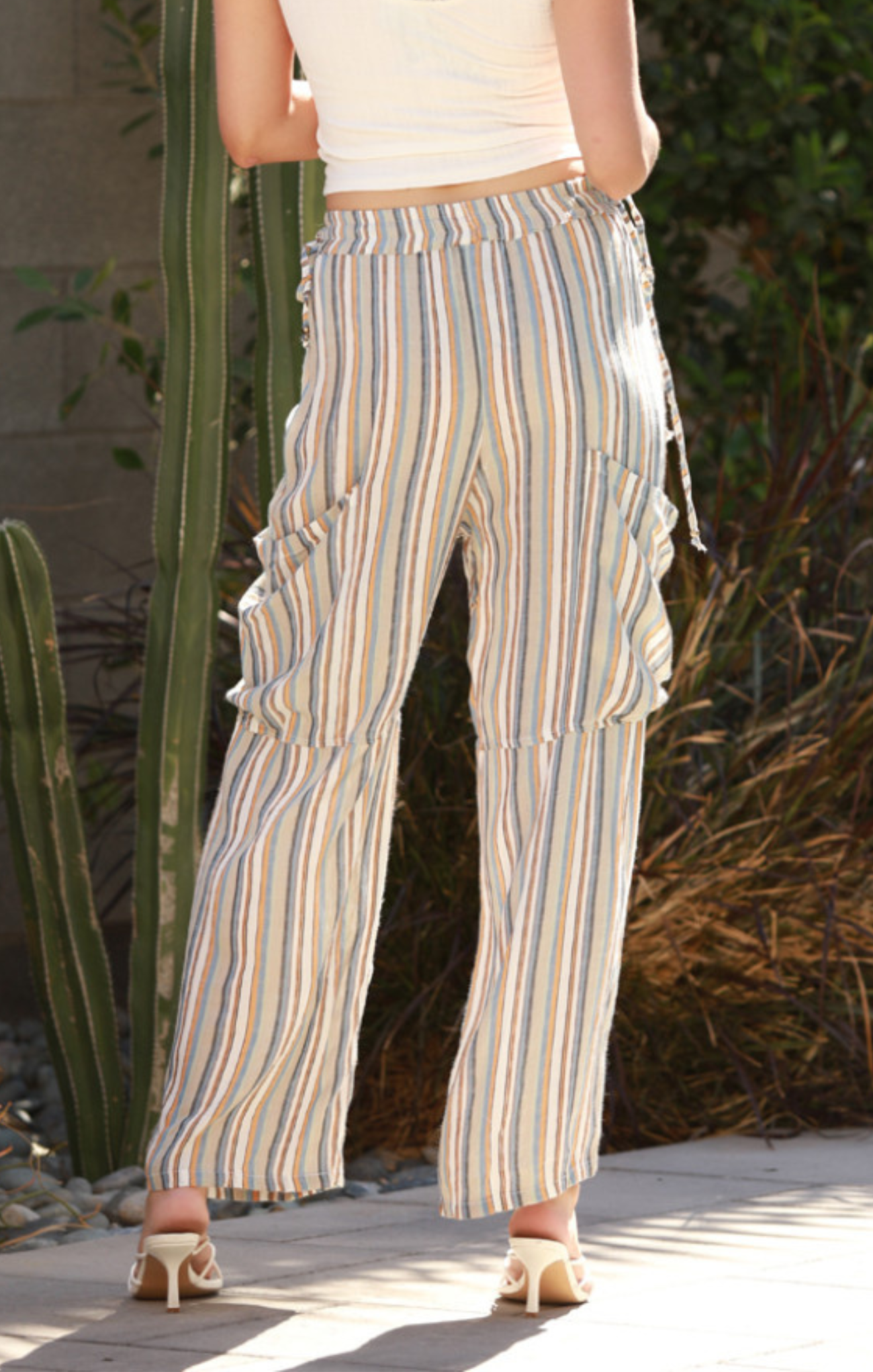 Person wearing striped pants standing outdoors with cacti in the background