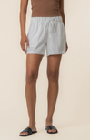 Person wearing light gray shorts on a beige background