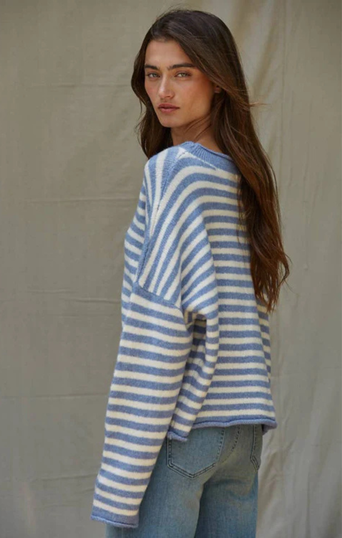 Woman wearing a blue and white striped sweater against a beige background