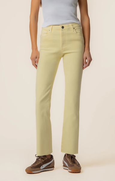 Person wearing light yellow jeans and brown shoes on a beige background