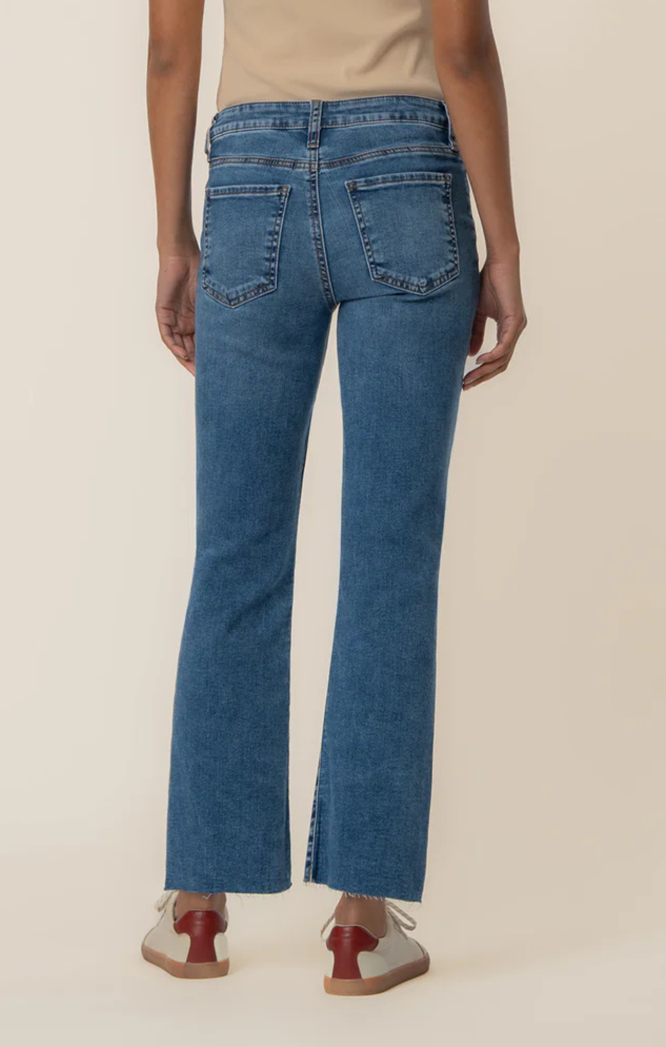 Person wearing blue jeans on a beige background