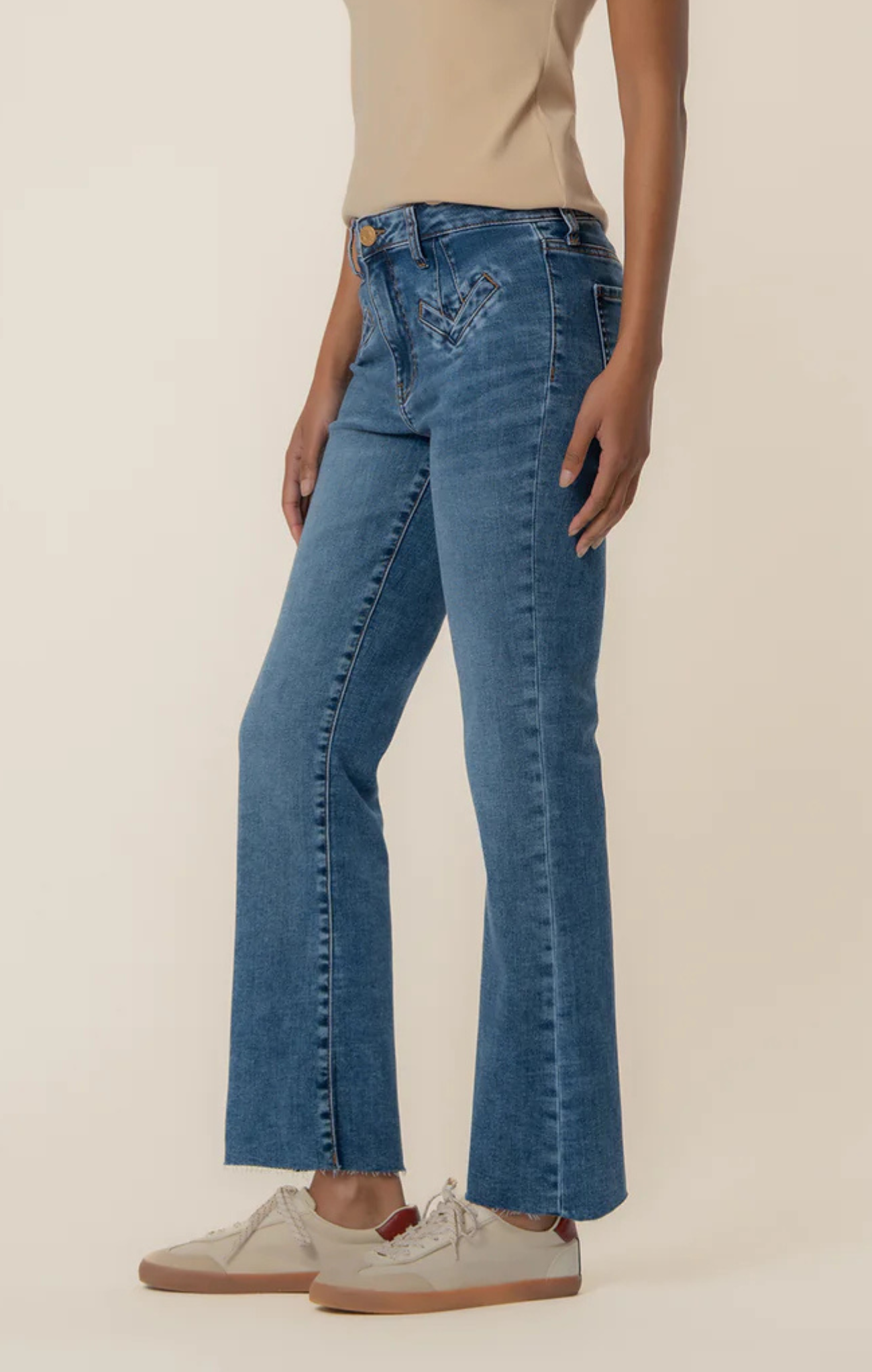Person wearing blue jeans and beige shoes on a plain background