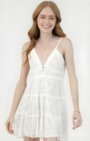 Woman wearing a white lace dress against a plain background