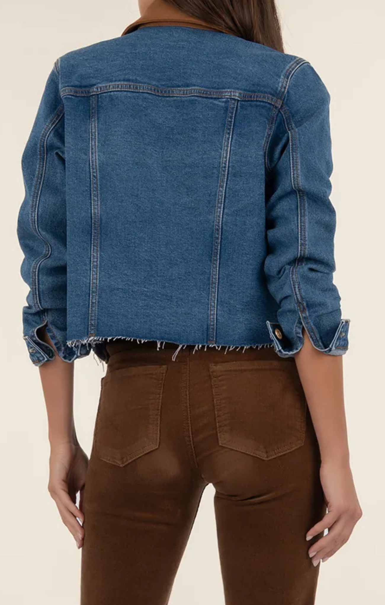 Blue denim jacket worn by a person on a beige background