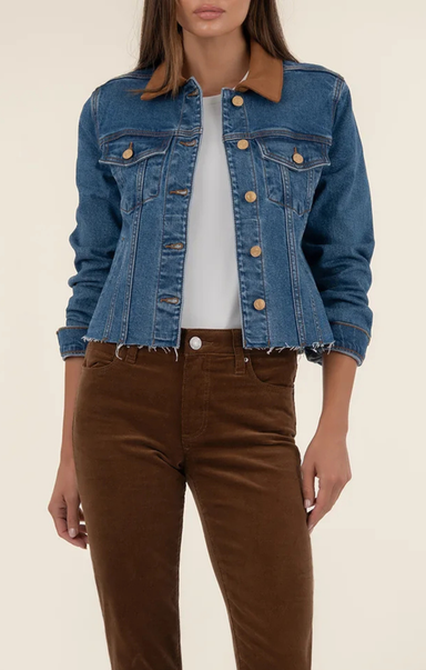 Person wearing a blue denim jacket over a white shirt and brown pants on a beige background