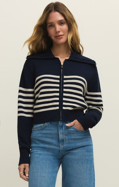 Woman wearing a navy and white striped sweater with a hood on a beige background