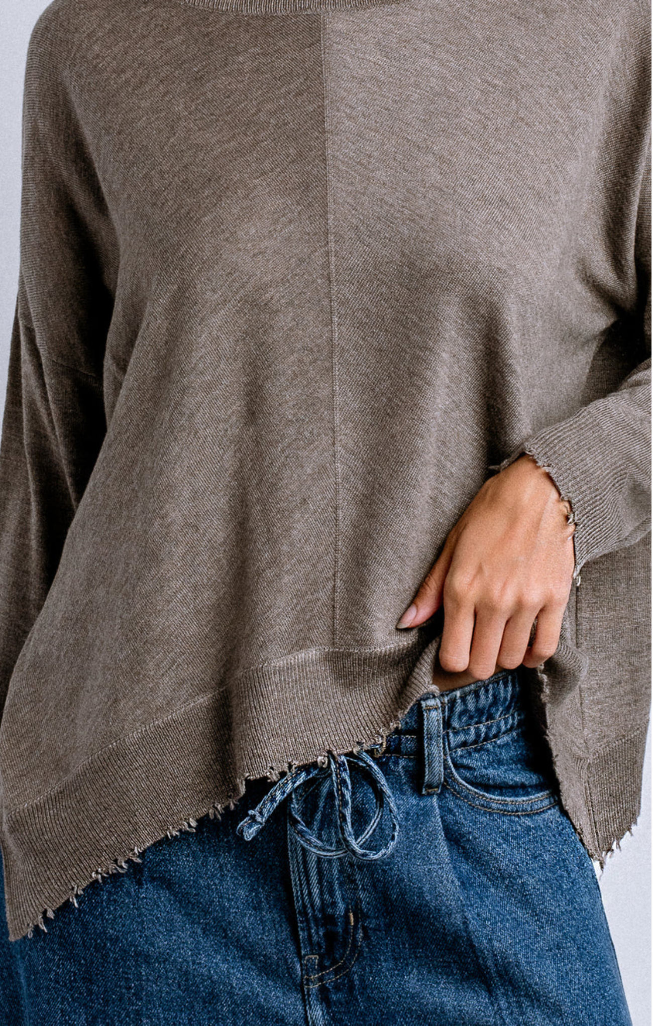 Brown sweater over blue jeans on a plain background