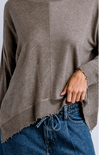 Brown sweater over blue jeans on a plain background