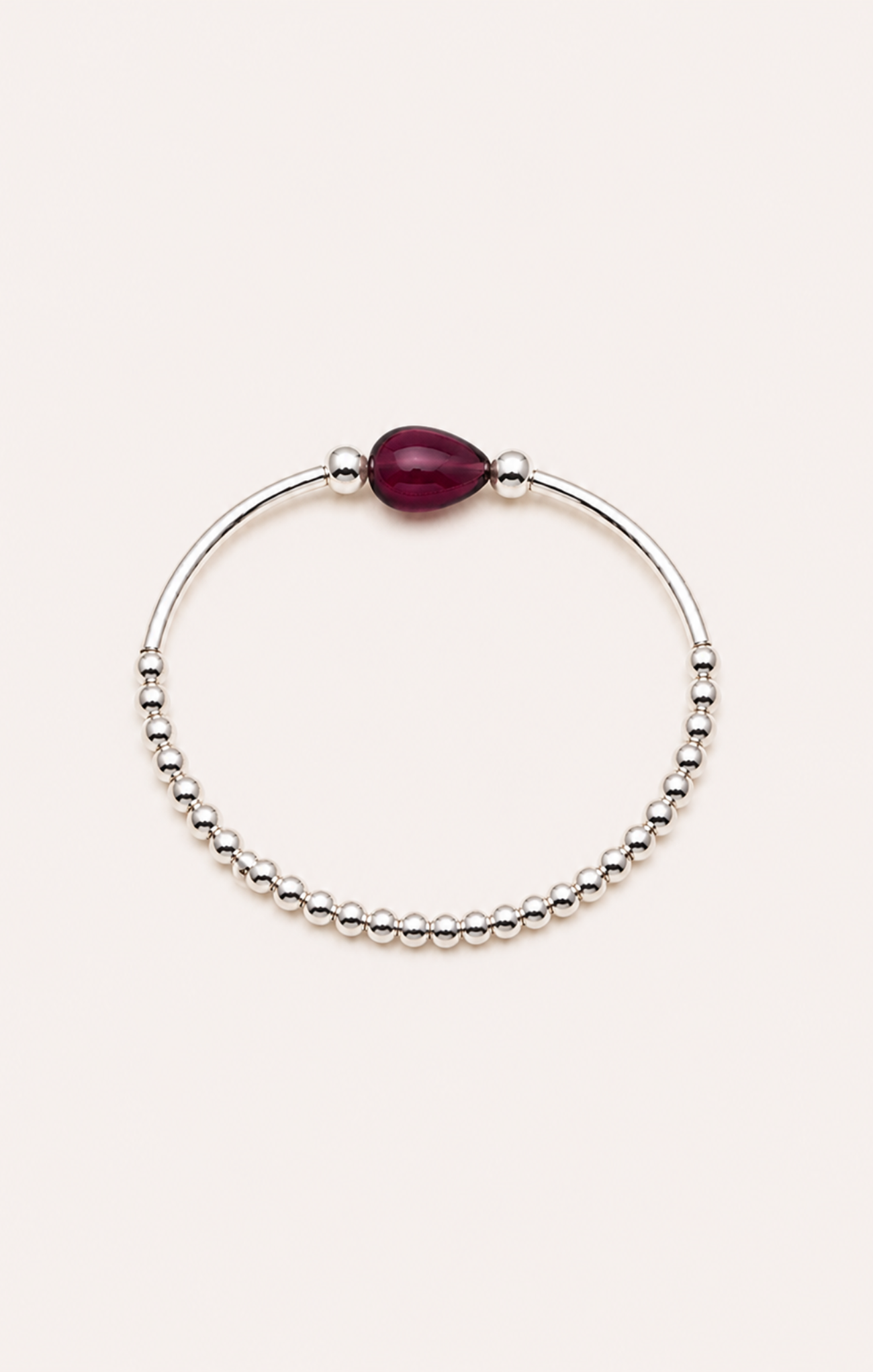 Bracelet with a red gemstone on a wrist against a beach sunset background