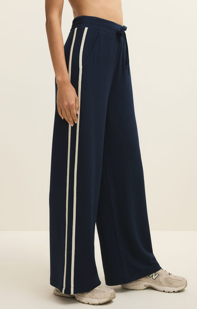 Navy blue wide-leg pants with white stripes on a neutral background