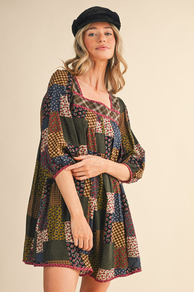 Woman wearing a colorful patterned dress and black cap against a beige background