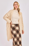 Woman wearing a beige cardigan and plaid skirt on a white background