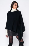 Woman wearing a black poncho over a white sweater and leather skirt on a white background