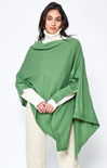 Woman wearing a green poncho over a white outfit on a white background