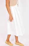 Person wearing a white skirt with gold buttons on a plain background