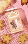 Gingerbread-themed skincare product set on a pink background with gingerbread cookies.