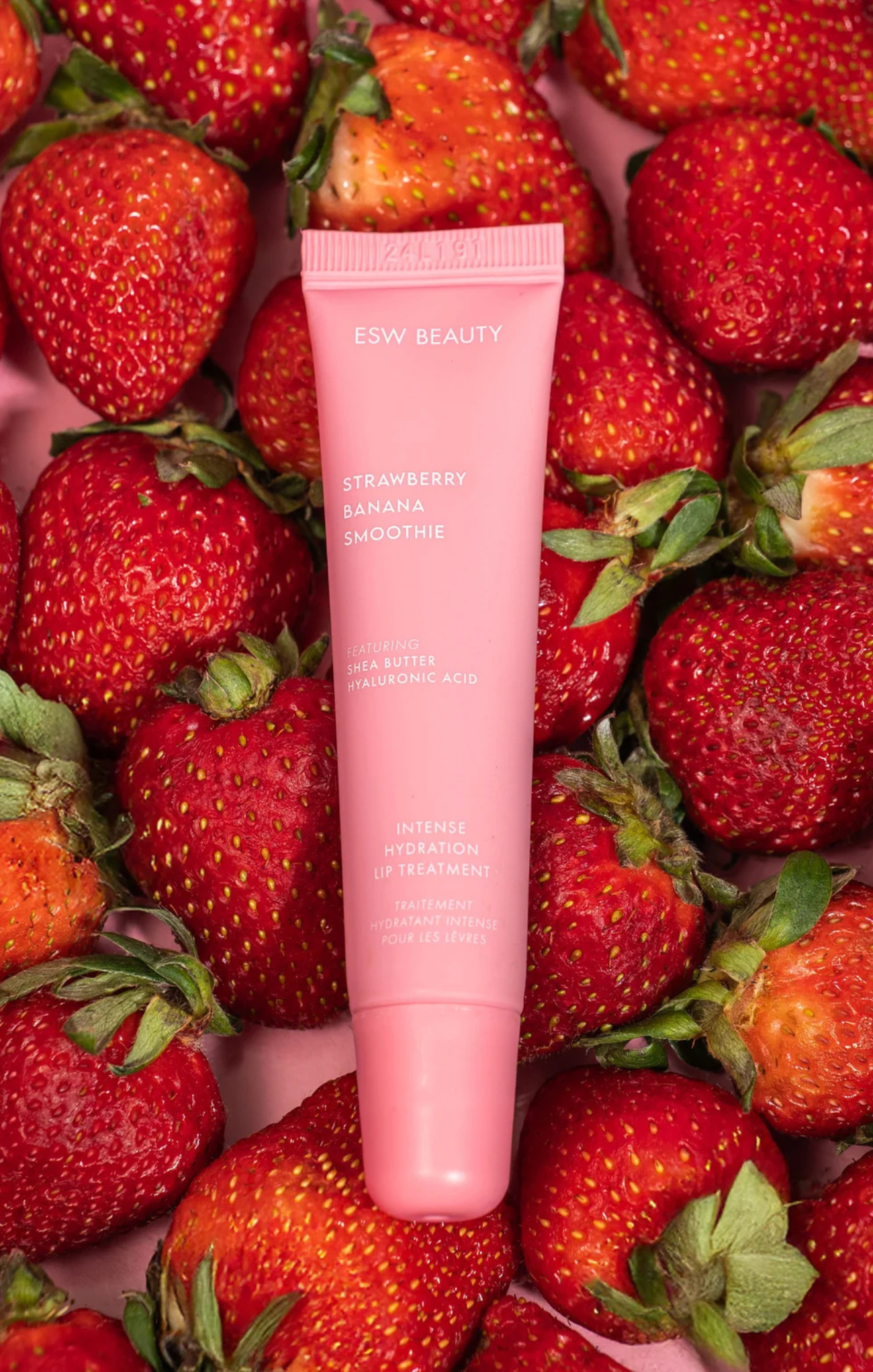 Pink skincare product surrounded by strawberries