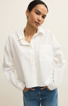 Woman wearing a white shirt and blue jeans against a plain background