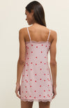 Woman wearing a pink slip dress with red heart patterns on a plain background