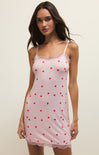 Woman wearing a pink slip dress with red heart patterns on a plain background