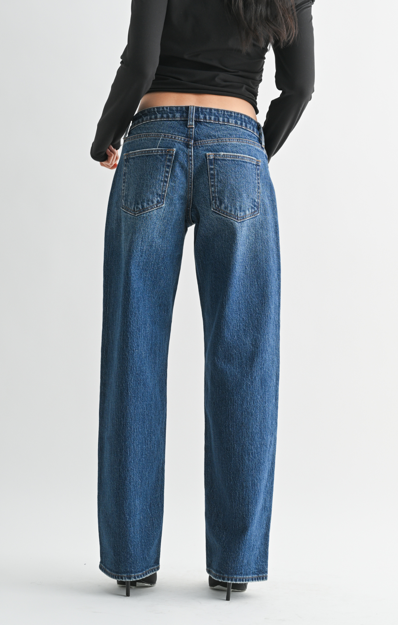 Blue jeans worn by a person on a plain background