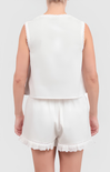Person wearing a white sleeveless top and shorts with lace trim on a plain background