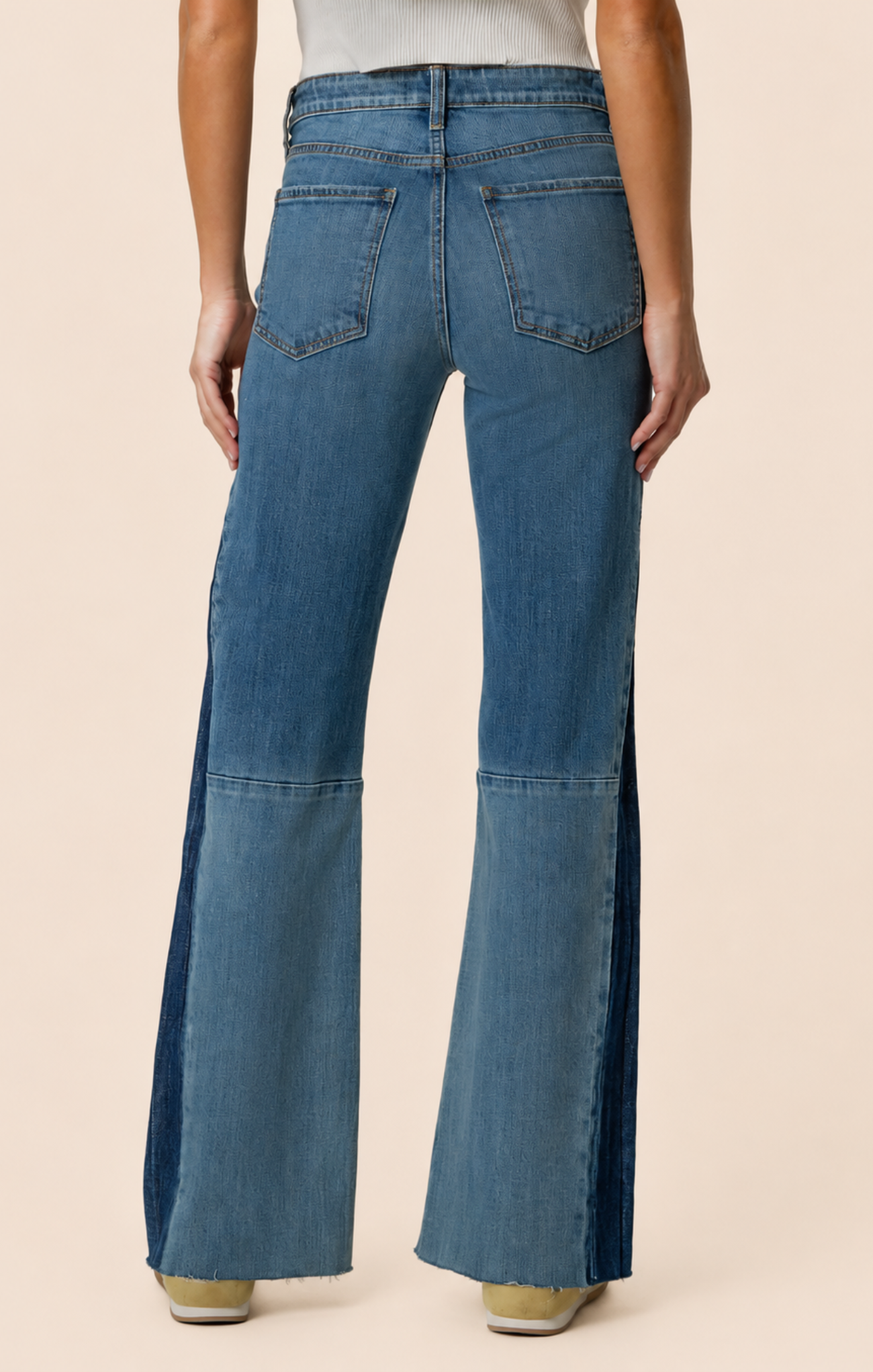Blue flared jeans worn by a person on a beige background