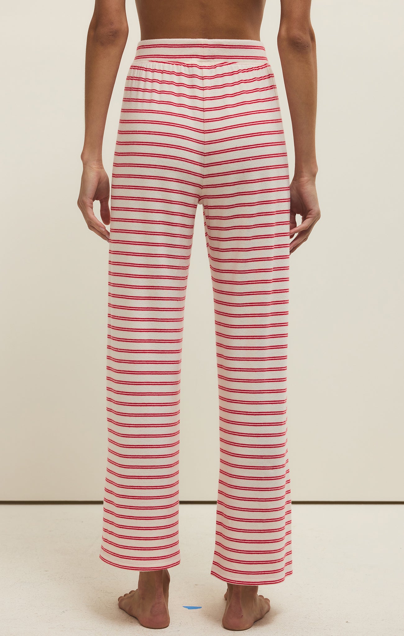 Red and white striped pants worn by a person on a beige background