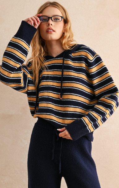 Person wearing a striped sweater and glasses against a beige background