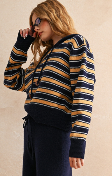 Woman wearing a striped sweater with navy and mustard colors against a beige background